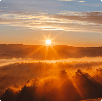 Sunrise over misty hills with golden rays