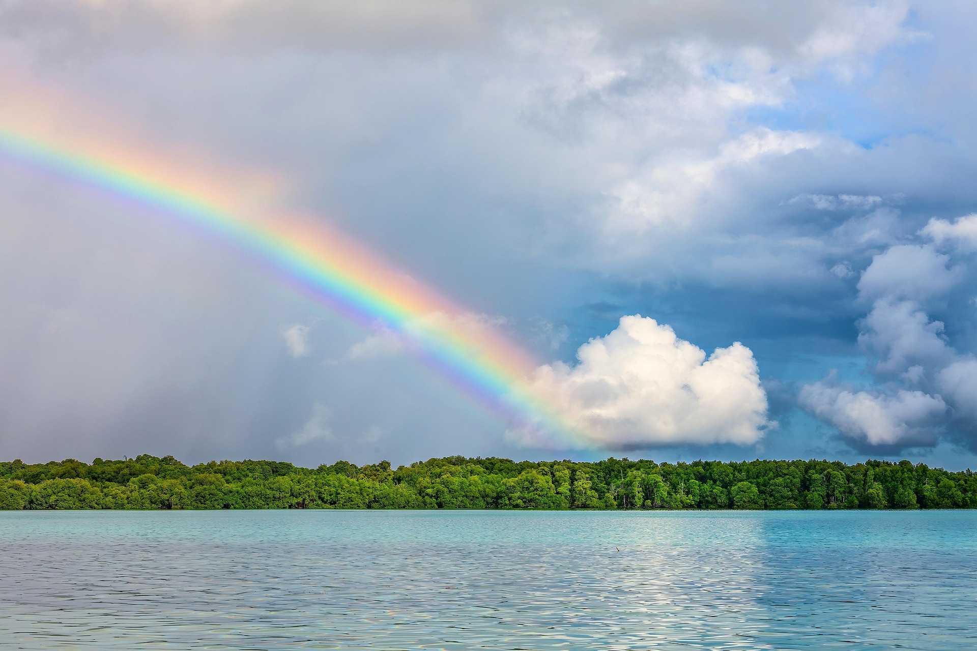 Rainbow over turquoise lake and forest